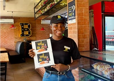 A Basilissa crew member holding a menu in a restaurant